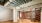 a room with a wood floor, brick walls, and windows