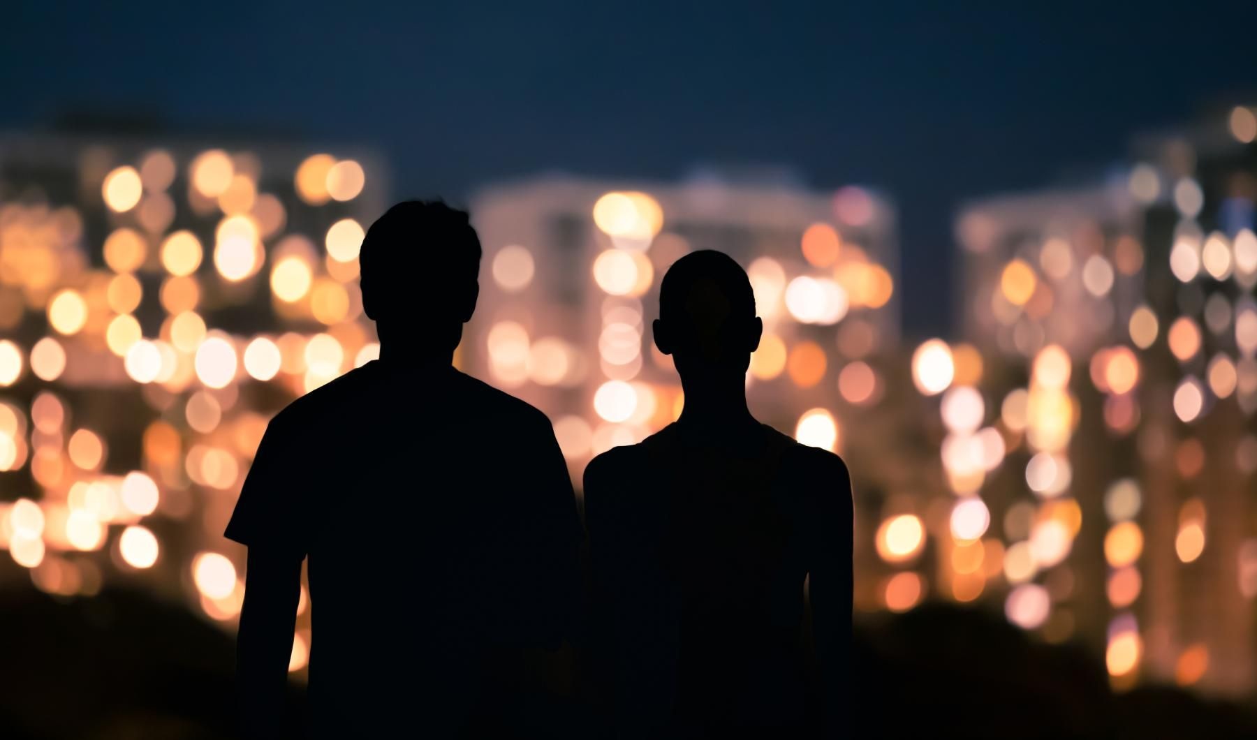 a man and a woman looking at a city at night